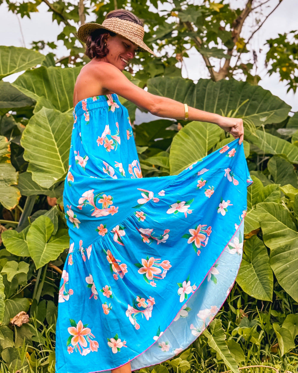 Woman wearing a blue floral dress standing among green plants