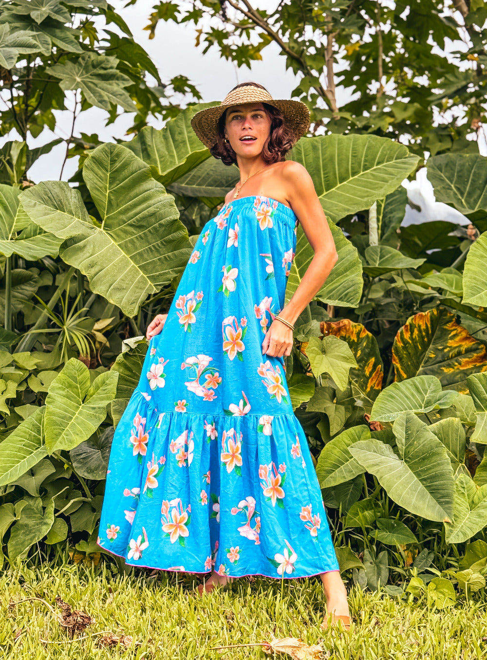 Woman in a blue floral dress standing in front of large green leaves hawaii strapless sundress kauai hanalei design