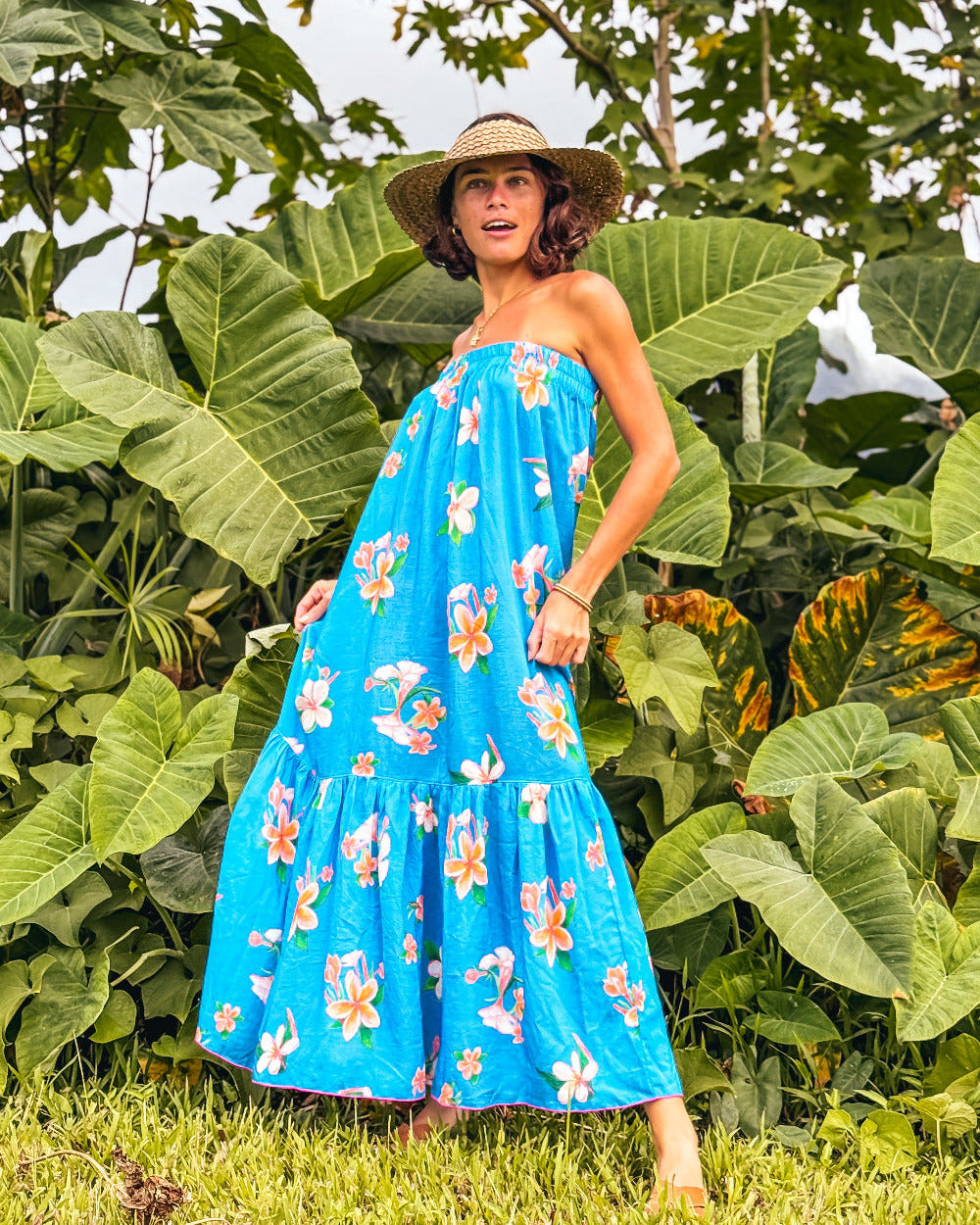 Woman in a blue floral dress standing in front of large green leaves hawaii strapless sundress kauai hanalei design
