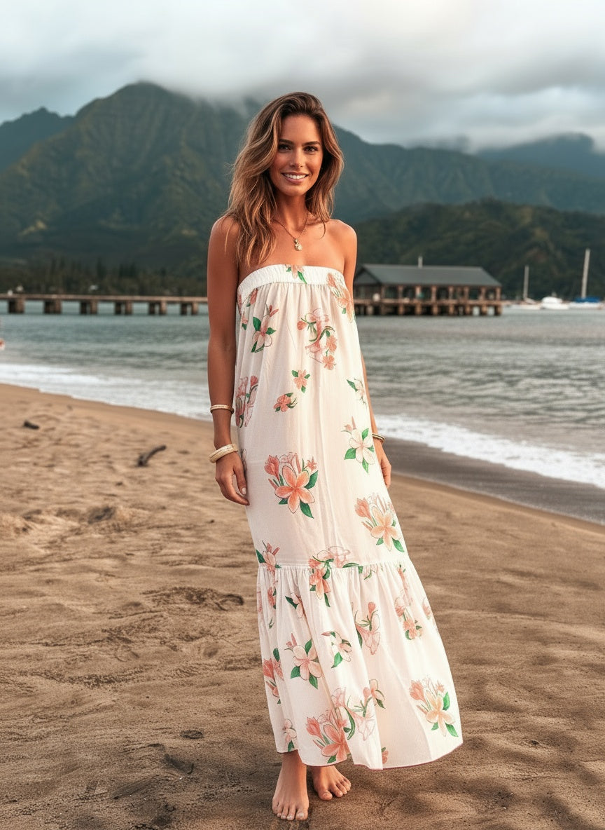 Woman in a floral dress standing on a beach with mountains in the background